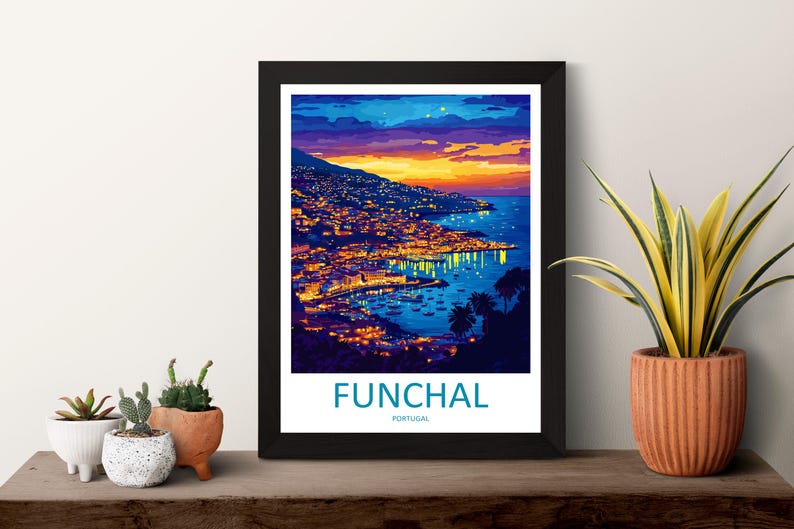 Op de afbeelding: Een ingelijste kunstdruk van Funchal, Portugal, bij zonsondergang. De afbeelding toont een kuststad met lichten die weerspiegelen op het water, onder een kleurrijke lucht. De print zit in een zwart frame, met de naam van de stad onderaan.