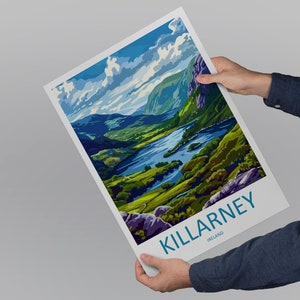 May include: A colorful poster with a scenic view of Killarney, Ireland. The poster features a lake surrounded by lush green hills and a blue sky with white clouds. The text "KILLARNEY, IRELAND" is printed in blue at the bottom of the poster.