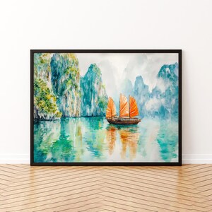 May include: Watercolour painting of a traditional boat with orange sails on a tranquil lake. The artwork features lush green and turquoise mountains in the background, framed in a black border.