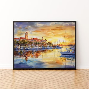 May include: A framed watercolour painting of a marina at sunset. The artwork shows boats, buildings, and palm trees under an orange and blue sky. The water reflects the warm colours of the sunset, creating a serene scene.