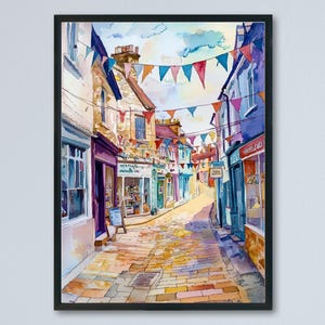 May include: A framed watercolour painting of a European street scene. The image shows a narrow cobbled street with colourful buildings and shops. Triangle flags are strung overhead, adding a festive atmosphere to the scene. The artwork is framed in black.