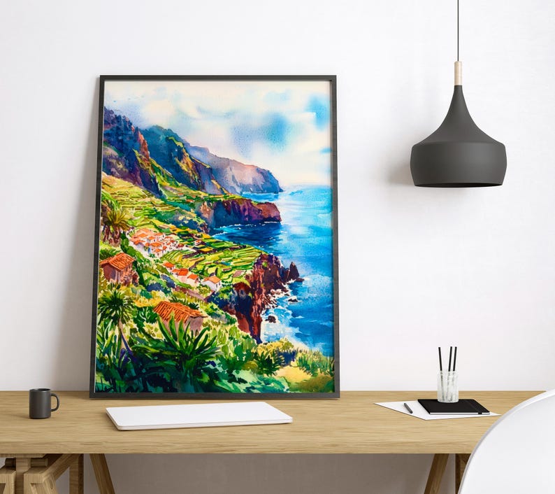 Pode incluir: Pintura em aquarela de uma paisagem costeira com fal&eacute;sias, oceano e edif&iacute;cios. A obra apresenta azuis, verdes e laranjas vibrantes, emoldurados em preto. A cena retrata um dia ensolarado com vista para o mar.