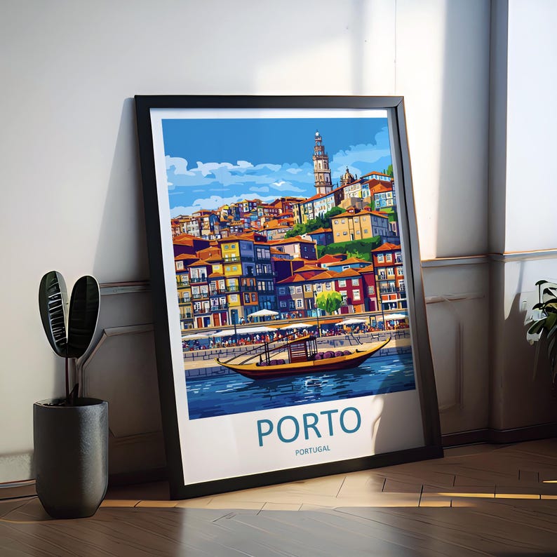 May include: A framed art print featuring a colorful illustration of Porto, Portugal. The artwork depicts buildings with orange rooftops, a river with a boat, and the text "PORTO" in a bold font. The print is in a black frame and leans against a white wall.