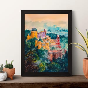 May include: A framed watercolor painting of a colorful castle complex nestled in a lush, green landscape. The artwork features buildings in shades of yellow, red, and purple, set against a backdrop of blue and green hills.