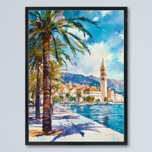 Könnte beinhalten: Aquarellmalerei einer Küstenstadt mit Palmen, einem hohen Glockenturm und Gebäuden am Wasser. Das Kunstwerk zeigt einen hellblauen Himmel mit flauschigen Wolken und einem ruhigen, türkisfarbenen Meer. Das Gemälde ist in einem schwarzen Rahmen gerahmt.