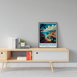May include: A framed poster featuring a colourful illustration of a tropical beach scene in Puerto Plata, Dominican Republic. The poster is on a wooden shelf with books and a potted plant.
