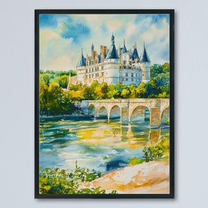 May include: Watercolor painting of a castle with multiple spires, set against a blue sky with clouds. A stone bridge arches over a river, reflecting the castle and sky. The artwork is framed in a black border.