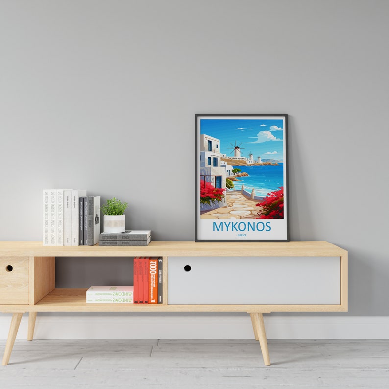 Puede incluir: Un p&oacute;ster enmarcado con una ilustraci&oacute;n colorida de una escena callejera en Mykonos, Grecia. El p&oacute;ster presenta edificios blancos, un cielo azul y un molino de viento. El texto "MYKONOS" est&aacute; impreso en la parte inferior del p&oacute;ster.