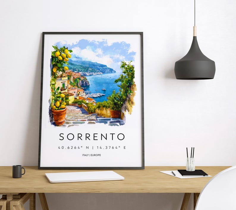 Puede incluir: Una impresi&oacute;n art&iacute;stica enmarcada de Sorrento, Italia, con una pintura de acuarela de un pueblo costero con mar azul, barcos y vegetaci&oacute;n. La impresi&oacute;n incluye el nombre de la ciudad y las coordenadas. El marco es negro.