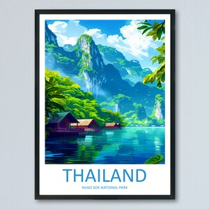 以下が含まれることがあります： 緑豊かな木々と山々に囲まれた湖の風景を描いた額装されたポスター。水は鮮やかな青色で、空と山を映し出しています。ポスターには「THAILAND KHAO SOK NATIONAL PARK」の文字が書かれています。