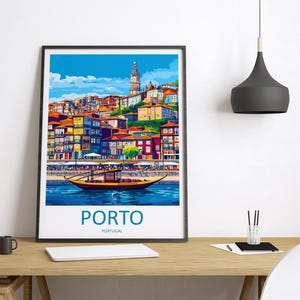 May include: A framed art print of Porto, Portugal, featuring a colorful cityscape with buildings and a river. A traditional boat floats on the water. The word "PORTO" is printed in teal below the image, with "PORTUGAL" underneath.