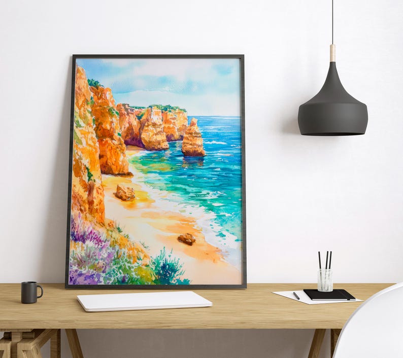 May include: A framed watercolor painting depicts a coastal scene with orange cliffs, a sandy beach, and turquoise water. The artwork features vibrant colors and a serene landscape, perfect for home decor.