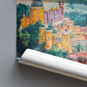 May include: Watercolor painting of a colorful castle complex with towers, domes, and walls. The buildings are painted in shades of yellow, purple, and red, set against a backdrop of green trees and a blue sky. The artwork is partially rolled.