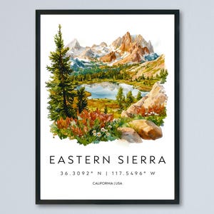 May include: Framed watercolour print of the Eastern Sierra mountain range. The artwork depicts a lake, trees, and mountains in shades of green, blue, and brown. Text at the bottom reads "EASTERN SIERRA" with coordinates and "CALIFORNIA | USA".