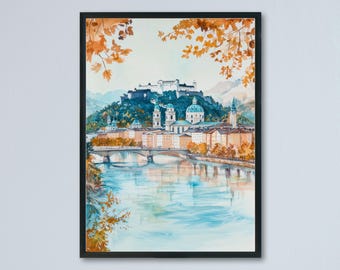 May include: Watercolor painting of a European city framed in black. The artwork depicts a river scene with a bridge, buildings, and a castle on a hill. The color palette includes blues, oranges, and greens, with autumn leaves in the corners.