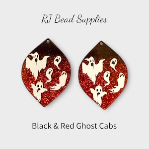 Peut inclure: Deux cabochons d'Halloween en forme de goutte d'eau avec une base rouge pailletée et des motifs de fantômes blancs. Les cabochons ont un dégradé noir et marron en haut. Le texte sur l'image indique "RJ Bead Supplies" et "Black & Red Ghost Cabs."