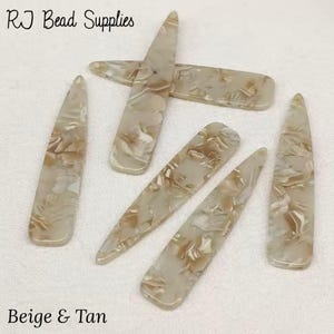 May include: Six beige and tan marbled plastic hair clips. The clips are long and narrow, with a slightly rounded end.  RJ Bead Supplies is printed in the top left corner of the image. Beige & Tan is printed in the bottom left corner of the image.