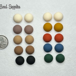 Peut inclure: Un ensemble de 20 perles rondes, plates, en argile polymère à finition mate, dans différentes couleurs, notamment blanc, marron, beige, orange, rouge, bleu, vert et noir. Les perles sont disposées en rangées de deux, chaque rangée présentant une couleur différente. Une pièce de monnaie canadienne de 25 cents est incluse pour référence de taille.