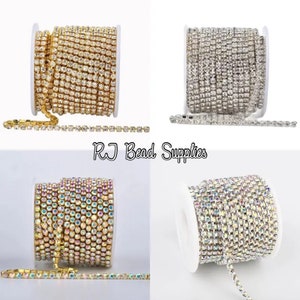 May include: Four spools of rhinestone chain, two with clear rhinestones, one with gold rhinestones, and one with iridescent rhinestones.  Each spool has a length of chain hanging off the spool.  The text "RJ Bead Supplies" is printed in the center of the image.