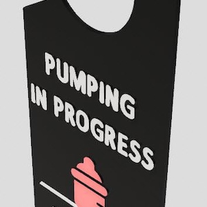 Puede incluir: Colgador de puerta negro con texto blanco que dice "Pumping in Progress" y "Please Do Not Disturb". Un icono de biberón rosa se encuentra en el centro del colgador.