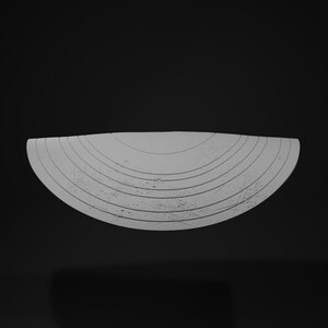 May include: A light gray, semi-circular object with concentric, textured lines. The object has a rough, weathered appearance and is set against a dark background. The design suggests a decorative or artistic piece.