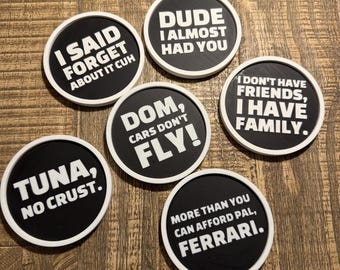 May include: A collection of six round black coasters with white rims and humorous white text. The phrases include "I SAID FORGET ABOUT IT CUH," "DUDE I ALMOST HAD YOU," and "DOM, CARS DON'T FLY!" Other coasters say "TUNA, NO CRUST," "I DON'T HAVE FRIENDS, I HAVE FAMILY," and "MORE THAN YOU CAN AFFORD PAL, FERRARI."
