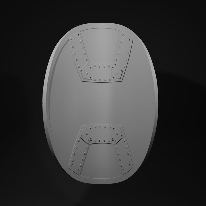 May include: A gray, oval-shaped shield with a riveted design. The shield features two distinct, geometric patterns near the top and bottom, each with a series of small, evenly spaced rivets. The overall design suggests a historical or fantasy theme.