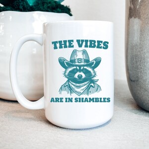 The Vibes Are In Shambles Raccoon 15oz Coffee Mug | Funny Trash Panda Cup | Weird | Vintage Cartoon | Mental Health | Meme | Strange