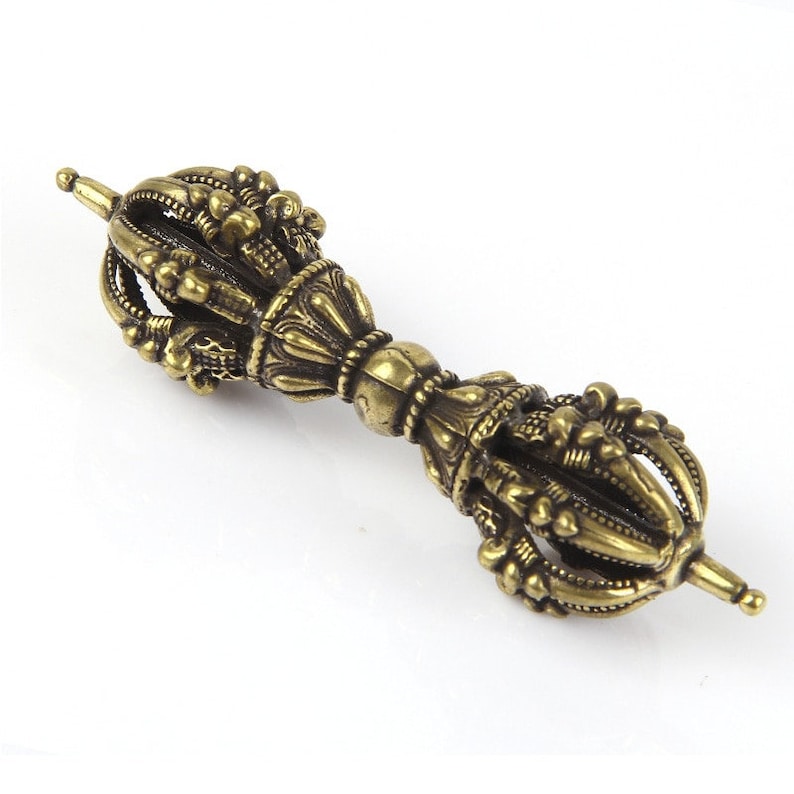May include: A gold-colored metal hand-held prayer wheel with intricate details and a pointed top.
