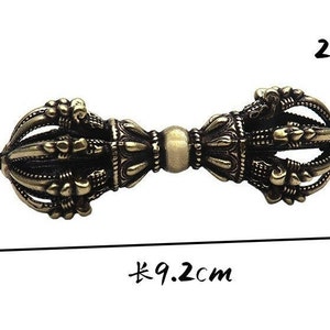 May include: A gold-colored metal prayer wheel with intricate details. The wheel is 9.2 inches long and 2.6 inches wide.