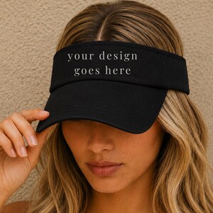 May include: A black visor featuring the text "your design goes here" in a light gray serif font centered on the front panel. The visor has a curved brim and an open top design, constructed from a solid fabric material with visible stitching.