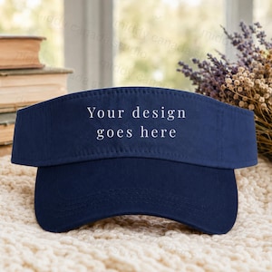 May include: A navy blue visor featuring the white text Your design goes here centered on the front panel. The visor has a structured crown and a curved brim, constructed from a solid fabric material with visible stitching along the edges.