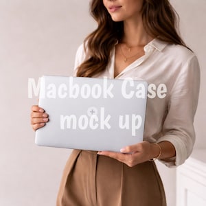 May include: A silver Macbook case mockup held by a person. The case has the words "Macbook Case mock up" printed on it in white. The person is wearing a white button-down shirt and brown pants.