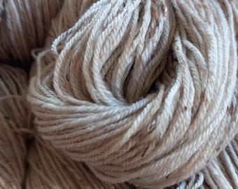 Può includere: Primo piano di un gomitolo di filato color crema con macchie marroni. Il filato è morbido e soffice, ed è perfetto per lavorare a maglia o all'uncinetto.