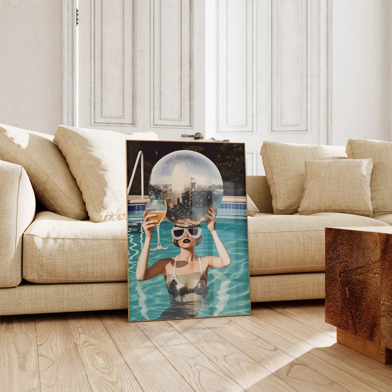 May include: A woman in a silver swimsuit and sunglasses holds a disco ball above her head while floating in a pool. The disco ball reflects the city skyline.