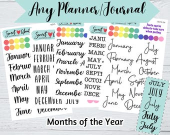 Op de afbeelding: Een verzameling stickervellen met de maanden van het jaar in verschillende zwarte lettertypes, waaronder script- en blokstijlen. De vellen bevatten kleurrijke ronde stickers en de tekst Any Planner/Journal en Months of the Year.