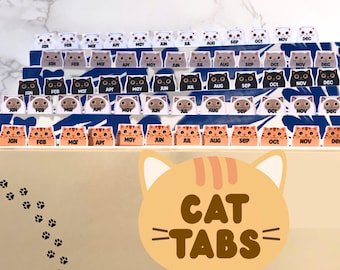 May include: A collection of cat-themed tabs, each labeled with a month from January to December. The tabs feature various cat designs in white, gray, black, and orange. The words "CAT TABS" are displayed in a playful font.