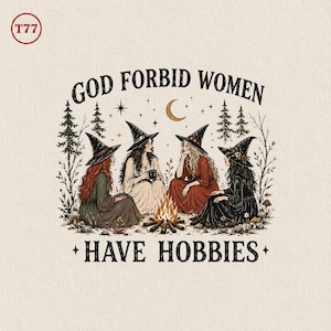 May include: A graphic illustration featuring four figures wearing pointed hats sitting around a campfire in a forest setting. The text "GOD FORBID WOMEN HAVE HOBBIES" is arched above and below the scene, which includes stars and a crescent moon.