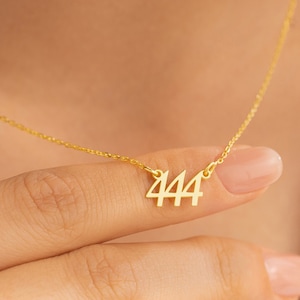 May include: A gold chain necklace with a pendant featuring the number 444.