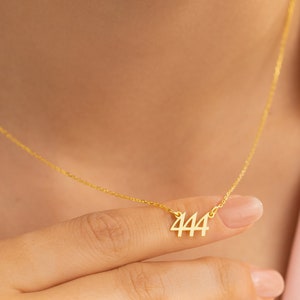 May include: A gold chain necklace with a pendant featuring the number 444.