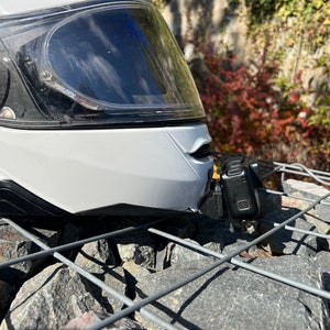 May include: A white motorcycle helmet with a clear visor and a black action camera mounted on the side.