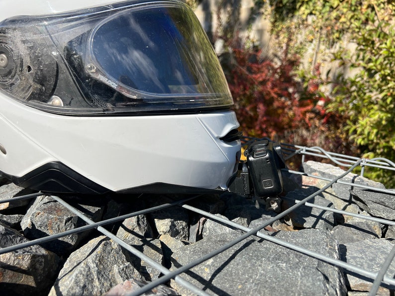 May include: A white motorcycle helmet with a clear visor and a black action camera mounted on the side.