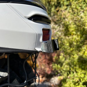 May include: A white helmet with a black and silver CityPluRider camera mount attached to the side.