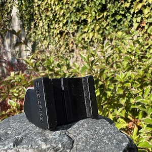 May include: Black plastic phone stand with the text "Remarkable" printed on the side. The stand is designed to hold a phone in a vertical position.