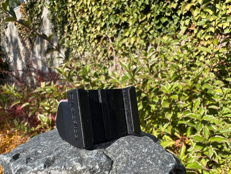 May include: Black plastic phone stand with the text "Remarkable" printed on the side. The stand is designed to hold a phone in a vertical position.