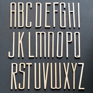 Puede incluir: Un conjunto de letras del alfabeto de madera en una fuente simple y moderna. Las letras son todas en may&uacute;sculas y est&aacute;n dispuestas en orden alfab&eacute;tico. Las letras est&aacute;n pintadas de blanco y tienen un aspecto ligeramente desgastado.