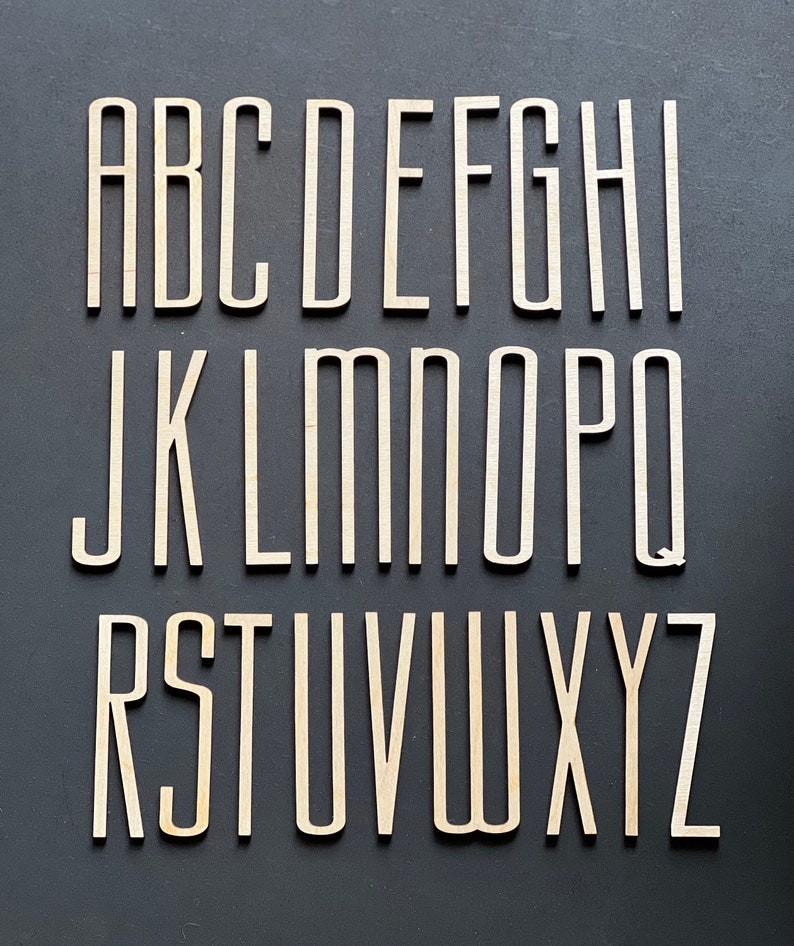 Puede incluir: Un conjunto de letras del alfabeto de madera en una fuente simple y moderna. Las letras son todas en may&uacute;sculas y est&aacute;n dispuestas en orden alfab&eacute;tico. Las letras est&aacute;n pintadas de blanco y tienen un aspecto ligeramente desgastado.