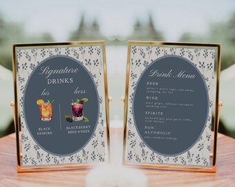 May include: Two framed drink menus with gold edges. One menu features "Signature Drinks" with "his" and "hers" drink options, including "Black Demure" and "Blackberry Bees Knees." The other menu lists "Drink Menu" with beer, wine, spirits, and non-alcoholic options.