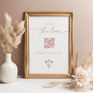 May include: A gold framed sign with the text "Capture the love" in pink script. A QR code is below the text with the instruction "Share your photos with us by scanning the code above".