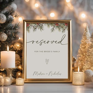 Op de afbeelding: Een printbaar huwelijksbord met een winters dennentakontwerp. Het bord zegt "gereserveerd voor de familie van de bruid" en bevat de namen van het paar, "Madison + Nicholas".
